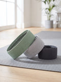Three fabric hip bands in sage, grey and graphite on a grey yoga mat
